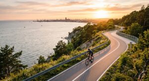A professional, high-angle editorial photograph of a cyclist riding along a scenic paved coastal bik