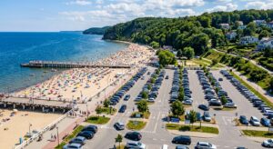 A high-angle professional editorial shot of a scenic summer beach in Gdynia or Gdańsk with a busy, w
