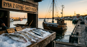 Professional editorial photograph of fresh, silver-scaled fish displayed on ice at a rustic wooden G